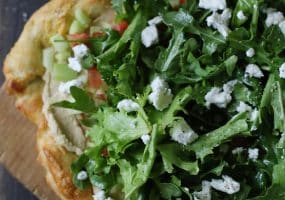 Pizza topped with fresh salad, fruit and cheese